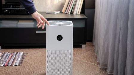 A close-up picture of a man using an air purifier in the living room