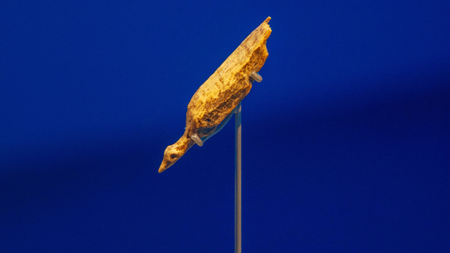 Small ivory diving bird sculpture pointed down at a 45-degree angle against a royal blue background